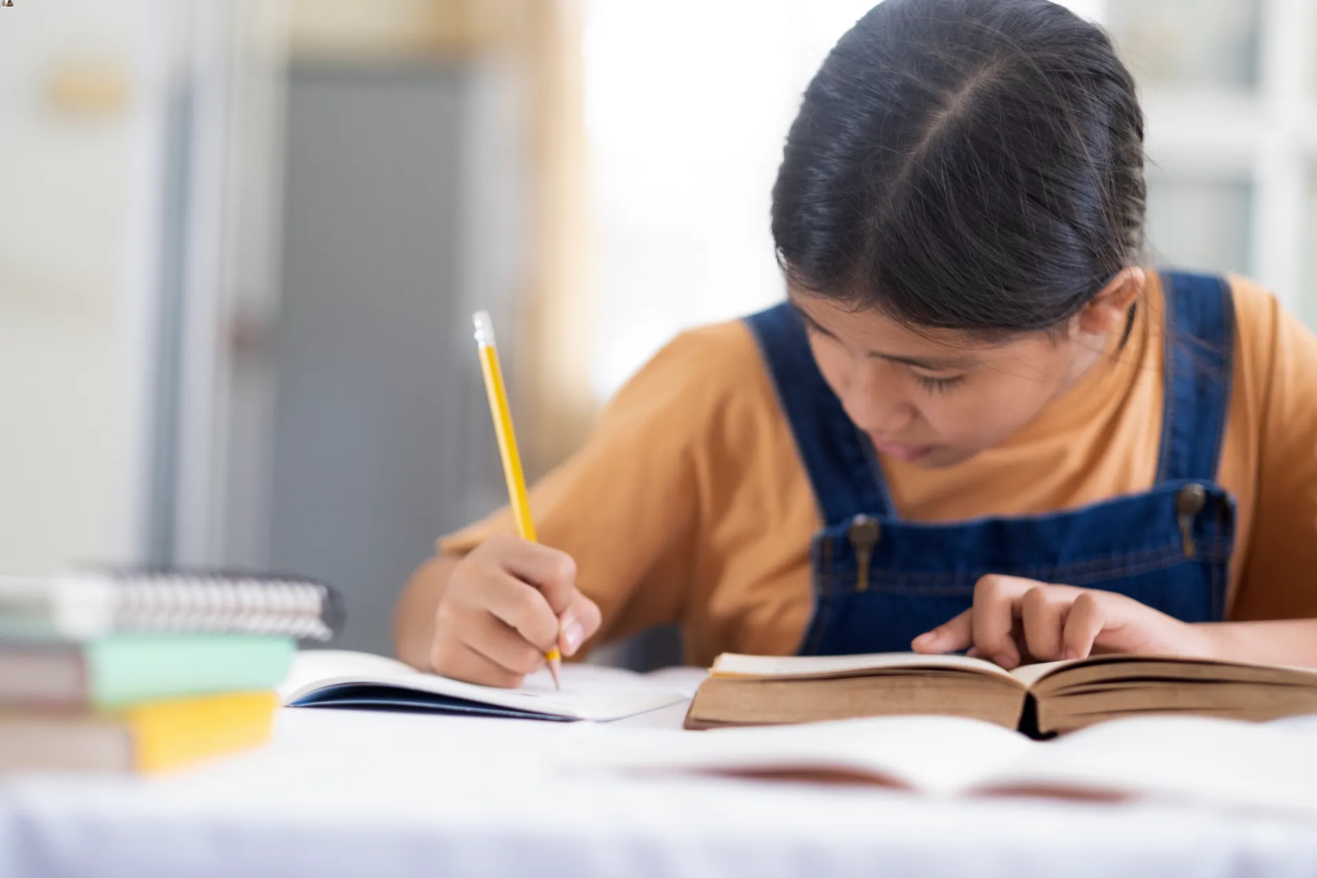 asian-girl-reading-and-doing-homework-at-her-home-2023-11-27-04-56-39-utc